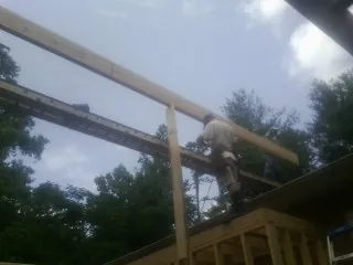 Carpenter setting a ridge beam over a new addition frame — Ice Dam Removal by Roofing Brothers in Adel