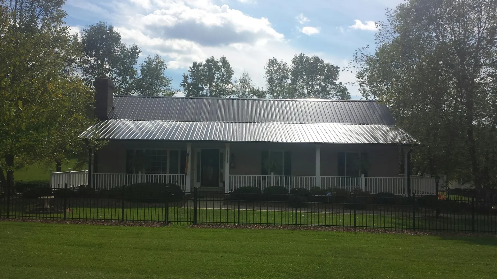 Gray metal roof on a brick ranch with a full width front porch — Gutter Guard Installation work by our crew in Adel
